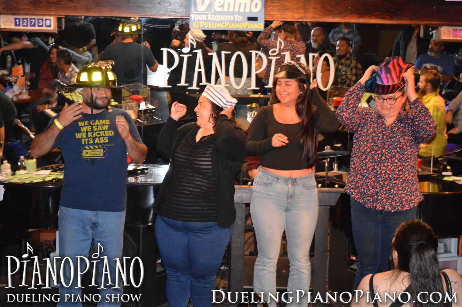 Group of guests wearing prop hats onstage at PianoPiano
